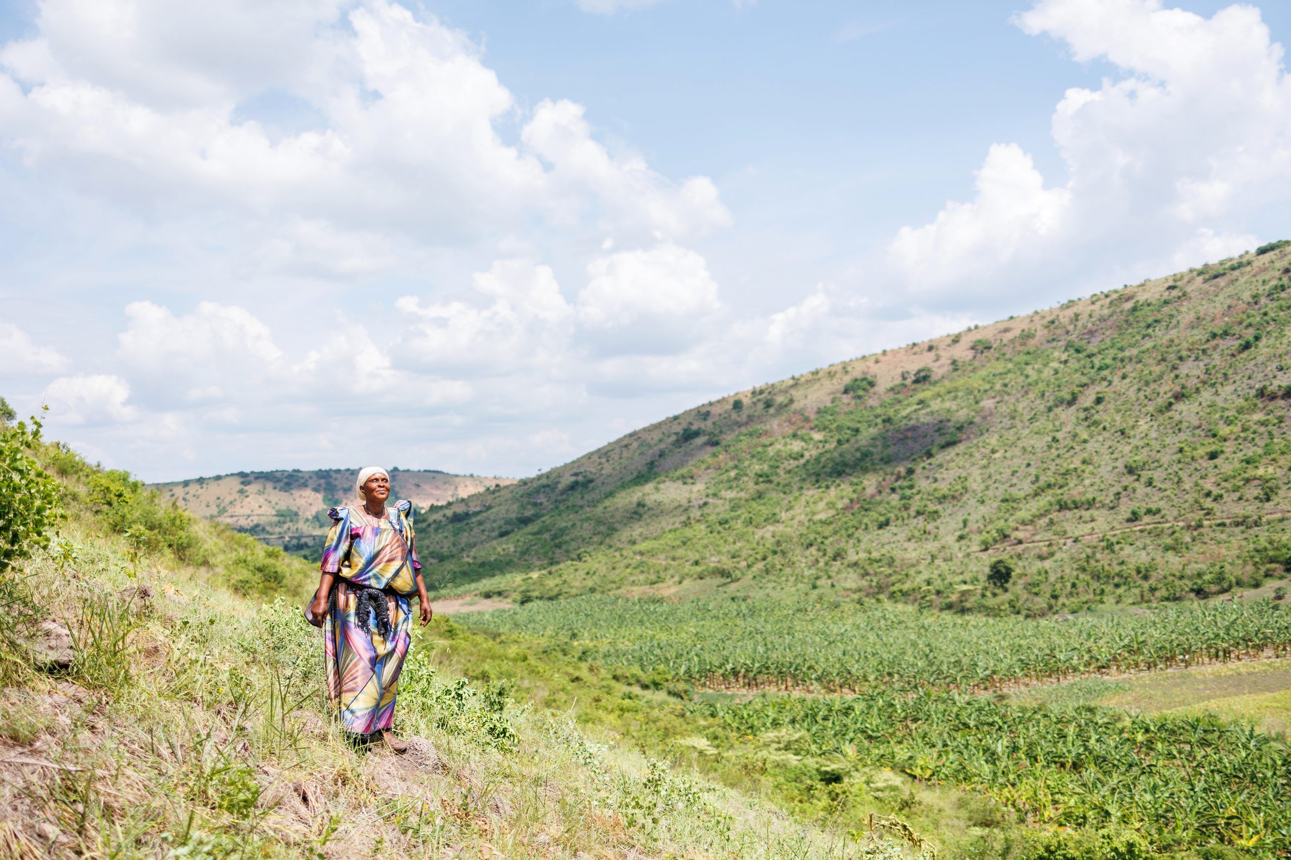 Kvinde smiler på en mark i Uganda