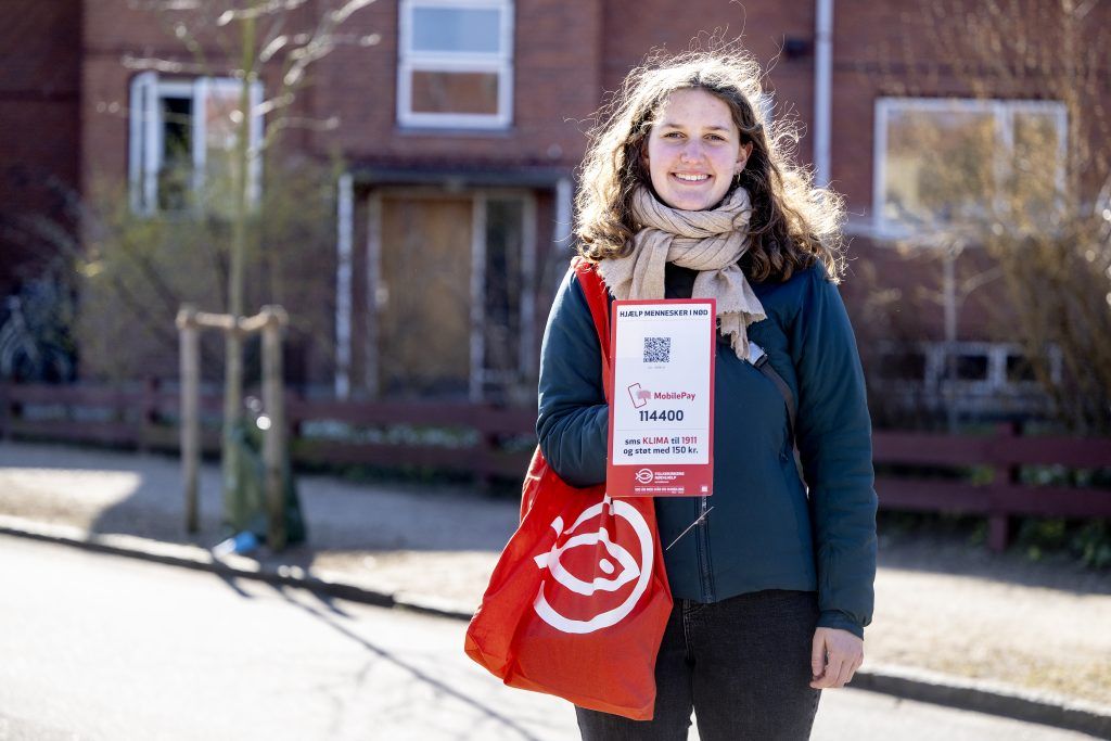 Kvindelig indsamler står med et MobilePay-skilt