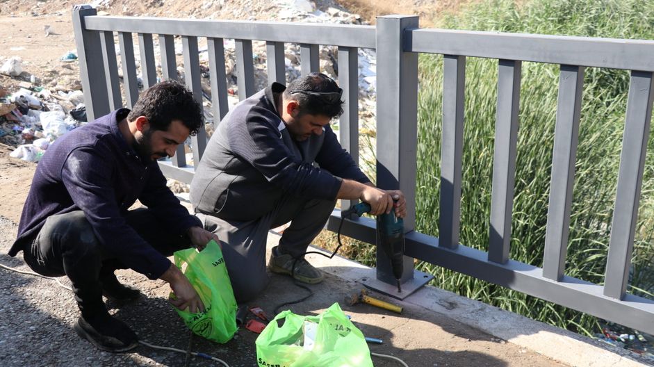 Two Men from sclr initiatives groups installing new bridge guardrails