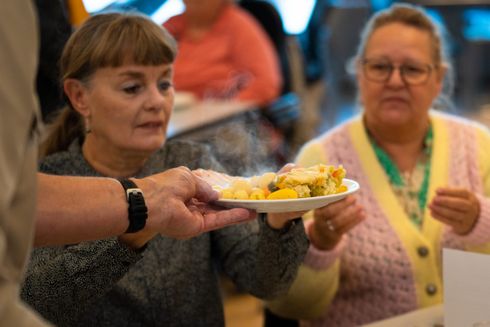 To kvinder får serveret en tallerken med aftensmad.