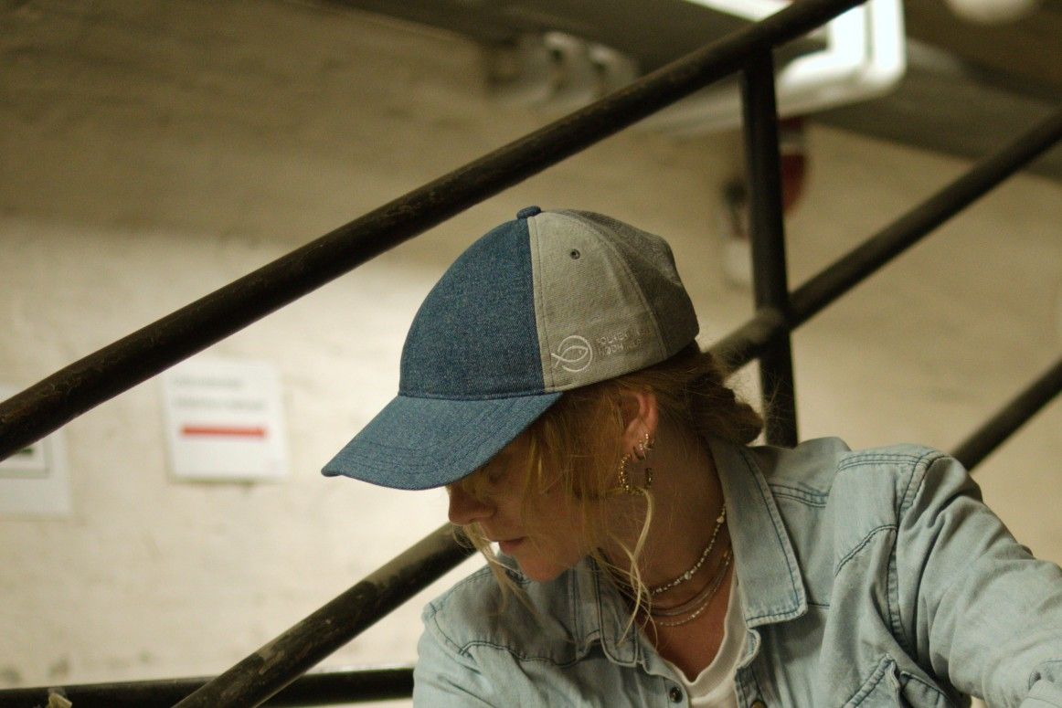 Kvinde med denim cap / kasket lavet af jeans, der ikke kunne sælges i Folkekirkens Nødhjælps genbrugsbutikker. Kasketten er udviklet i samarbejde med danske VAER.