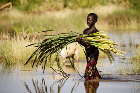Ung kvinde løfter grønt mens hun går i vand
