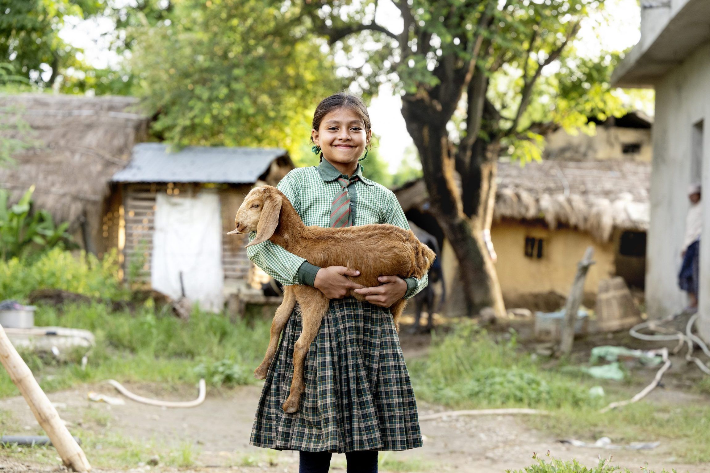 Yngre pige i ternet skjorte står med et lille gedekid