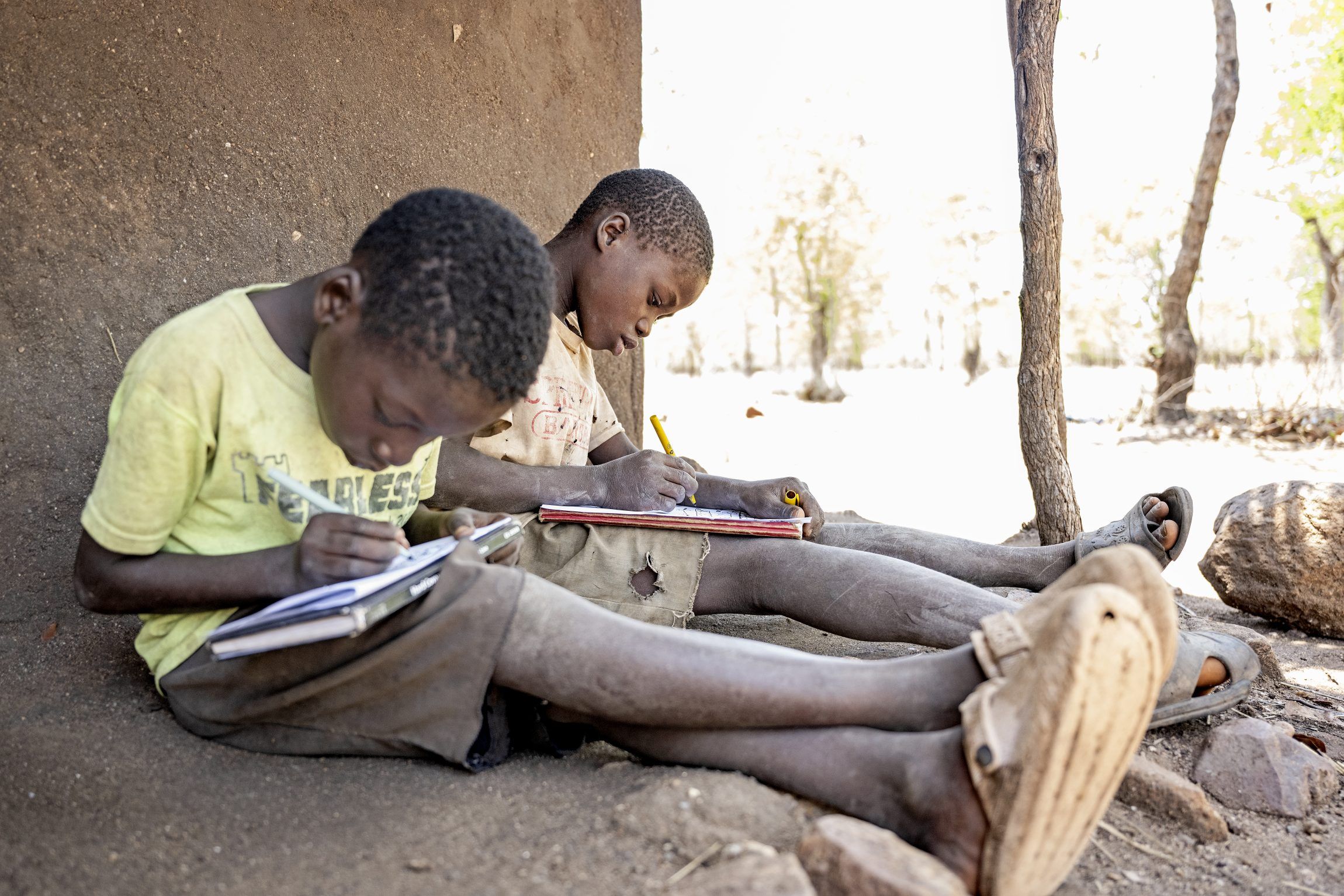Two children sitting and writing in a book