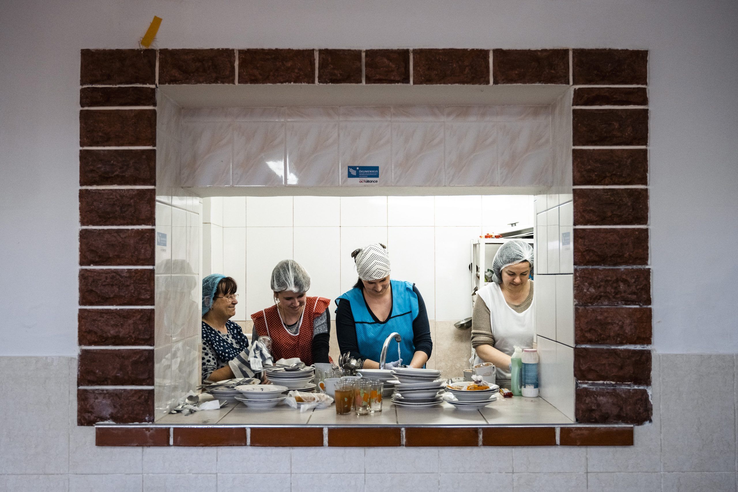 Fire kvinder vasker op i et køkken.