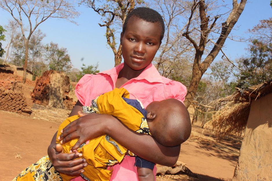 Ung kvinde sidder med sit barn i skødet