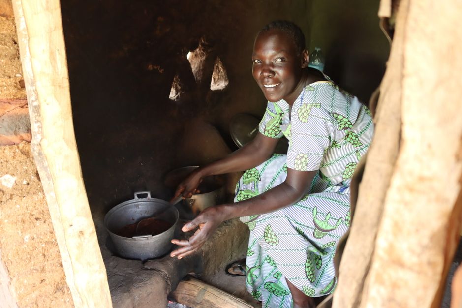 Eva Poni prepares a meal using a Lorena energy-saving stove inside her home in Imvepi Refugee Settlement.
