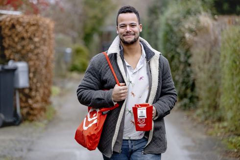 Ung mand går udenfor med rød indsamlingsbøsse