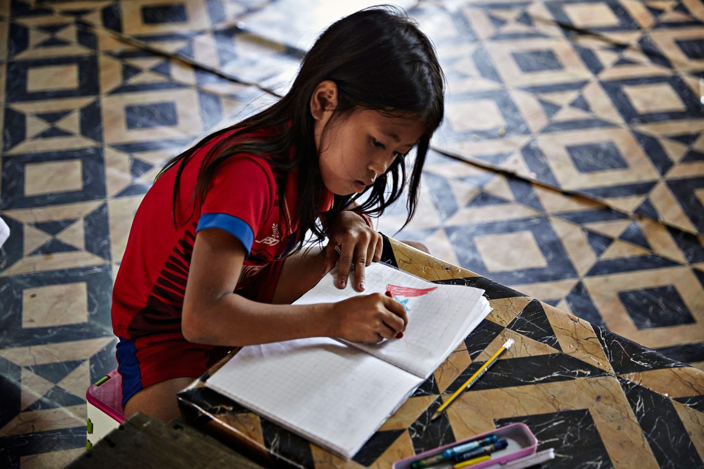 Pige tegner og farver i sin notesbog