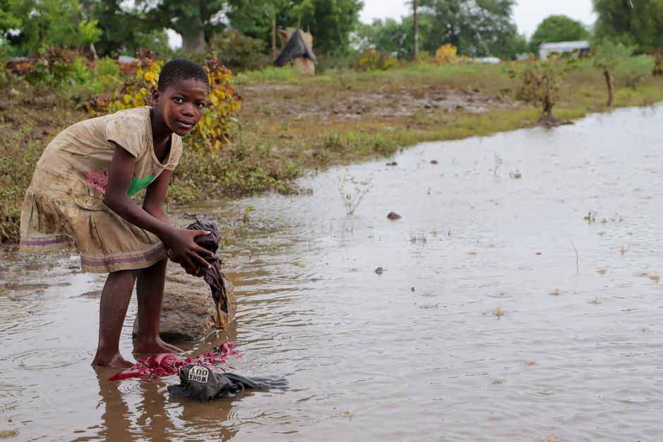 Pige vasker tøj i regnvejr