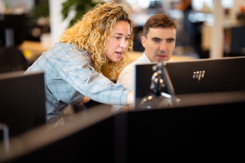 To medarbejdere fra Folkekirkens Nødhjælper kigger på en computerskærm sammen