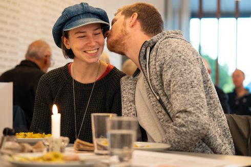 Et ungt par sidder og spiser deres aftensmad til fællesspisning.