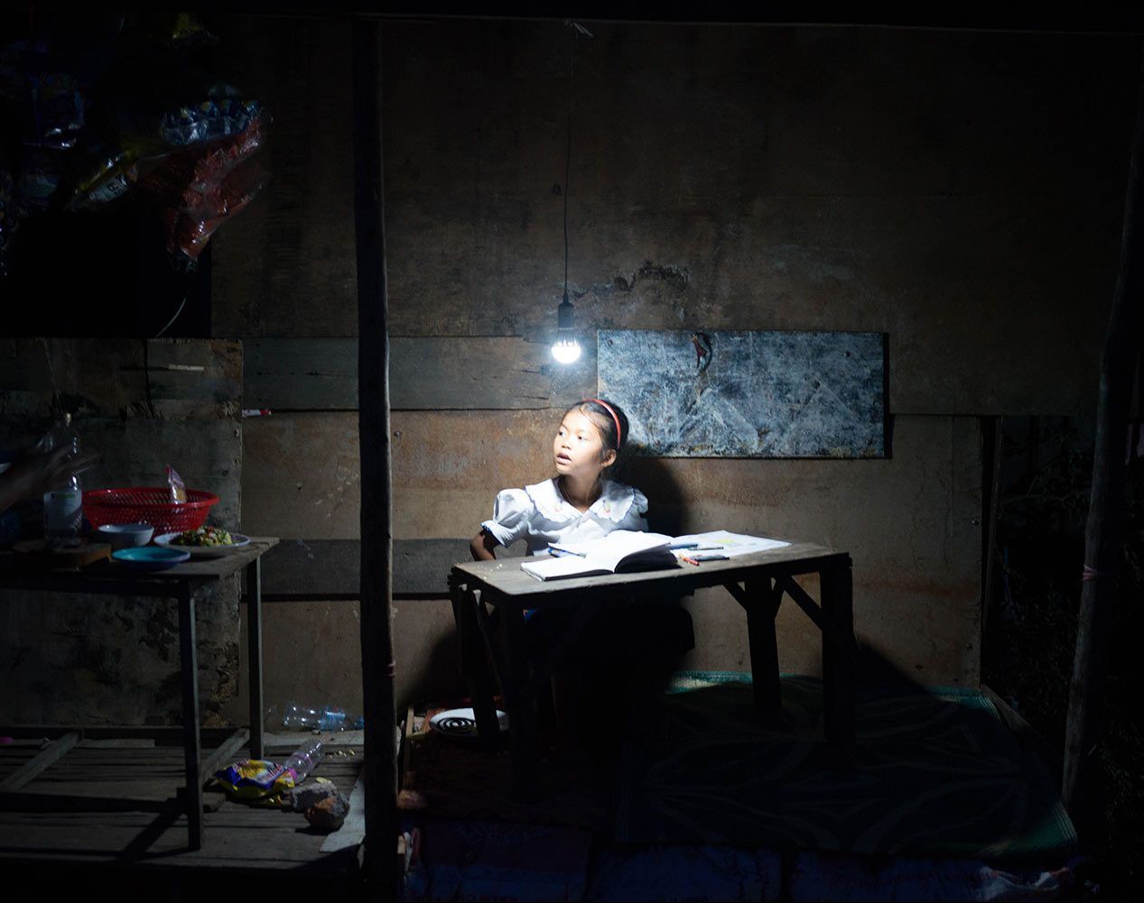 Thida på otte år læser lektier under lyset fra sin solcellelampe