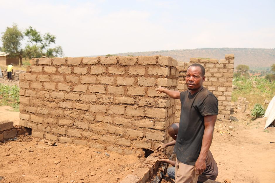 Bahati Seba Zungu, leader of the Tushirikiani Volunteer Group in Nakivale refugee settlement, points to a shelter under construction for newly arrived refugees.