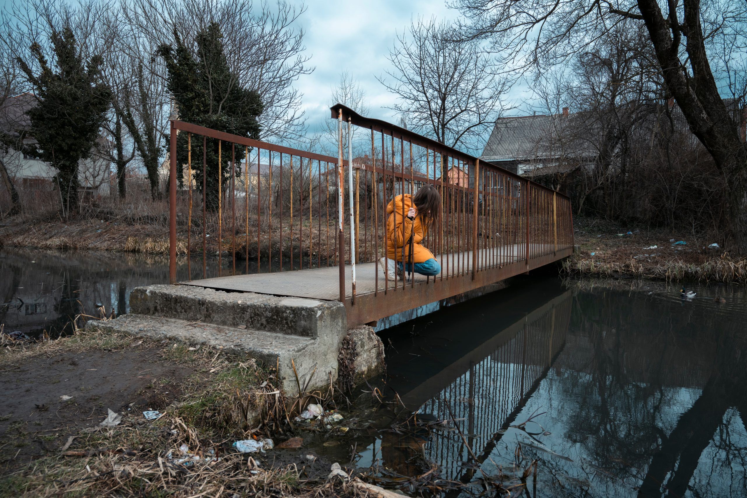 10-årig pige kigger i vanden fra en lille bro