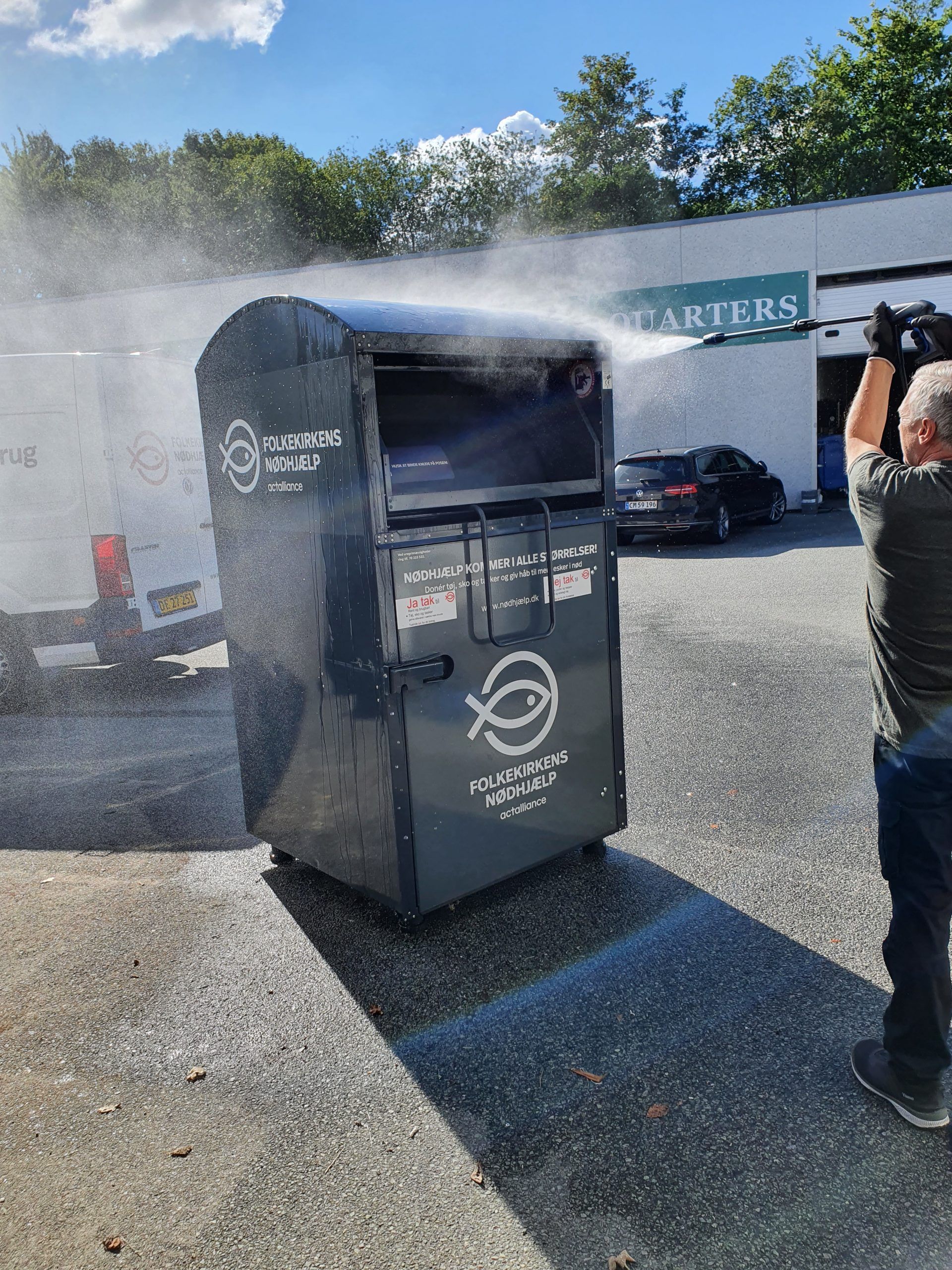 Medarbejder rengører en container fra Folkekirkens Nødhjælps genbrugskoncept