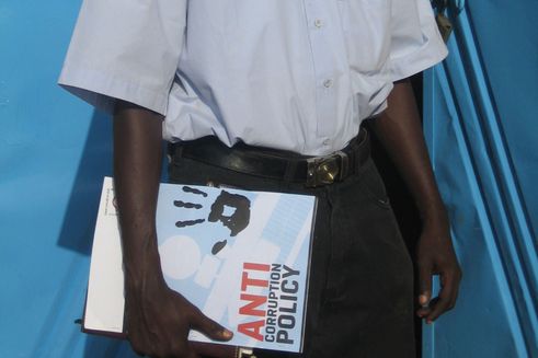 Mand står med mappe, hvor der står anti-korruptionspolitik på
