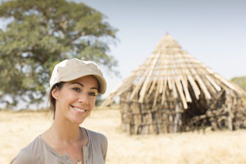 H.K.H. Prinsesse Marie smiler med en stråhytte i baggrunden