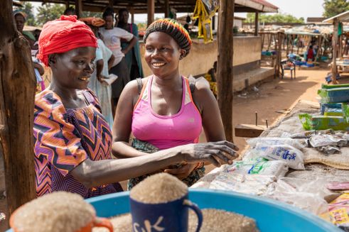Beatrice står med en kunde i hendes butik, hvor hun sælger dagligvarer i den sydsudanesiske by Magwi.