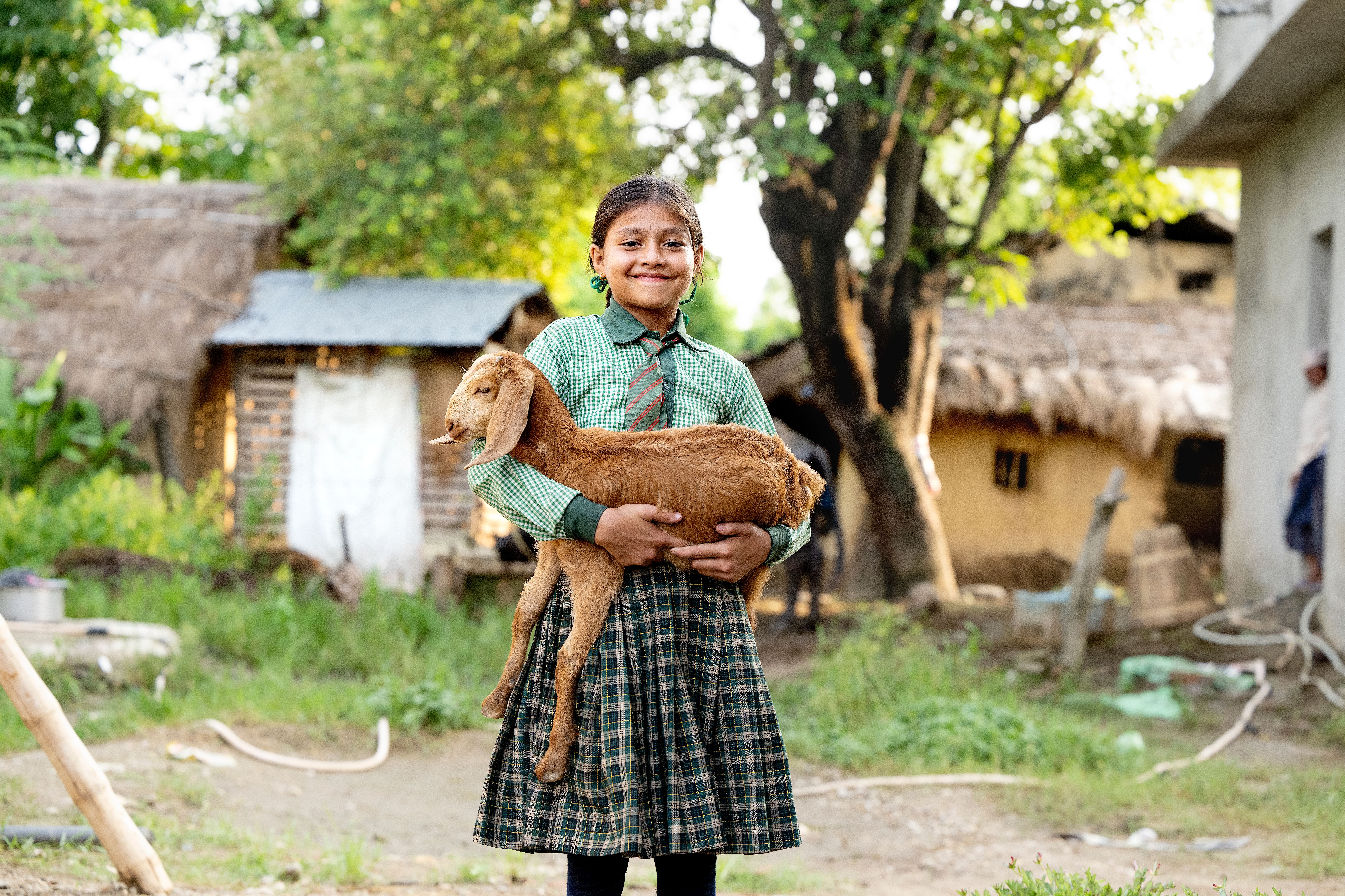 Yngre pige i ternet skjorte står med et lille gedekid